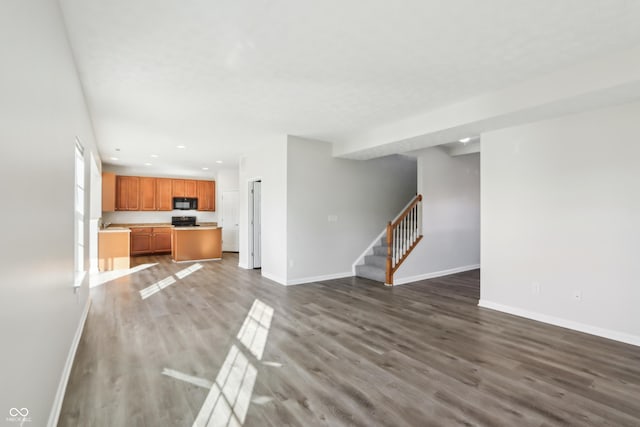 unfurnished living room with recessed lighting, stairs, baseboards, and wood finished floors