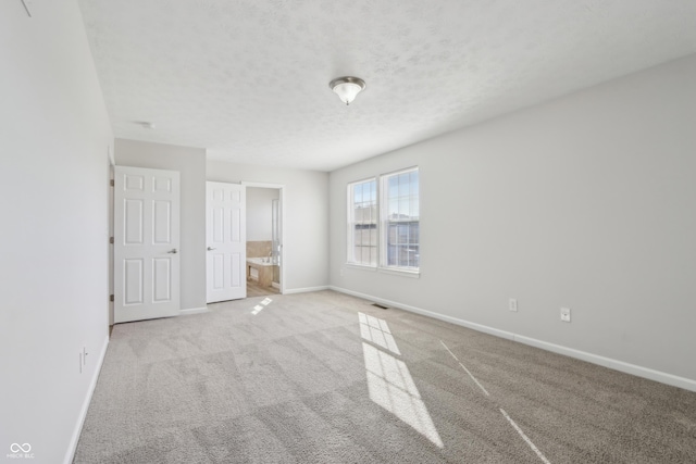 unfurnished bedroom with carpet, visible vents, baseboards, a textured ceiling, and connected bathroom