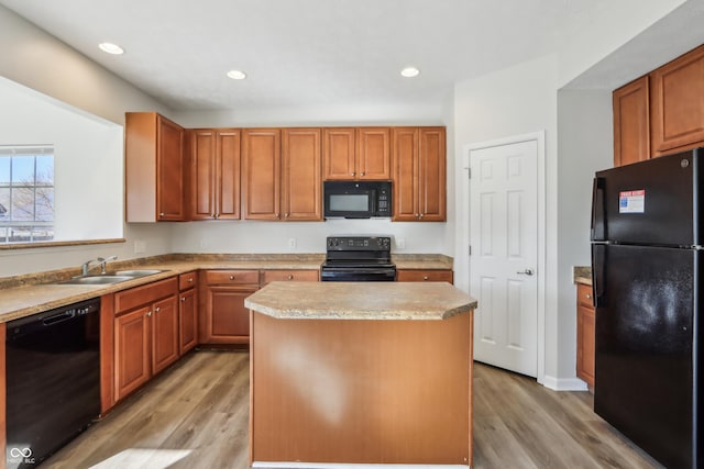 kitchen with black appliances, light wood-style flooring, a center island, recessed lighting, and light countertops