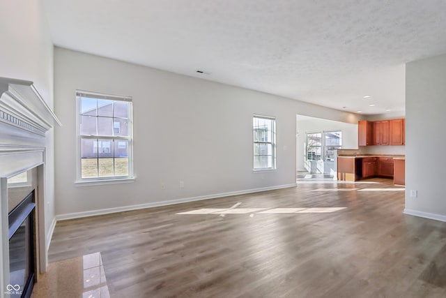 unfurnished living room featuring visible vents, baseboards, a fireplace with flush hearth, recessed lighting, and light wood-type flooring