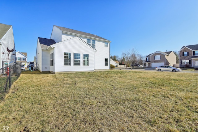 back of property with a lawn, fence, and a residential view