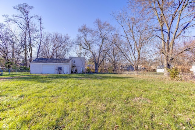 view of yard featuring a detached garage, an outdoor structure, and fence