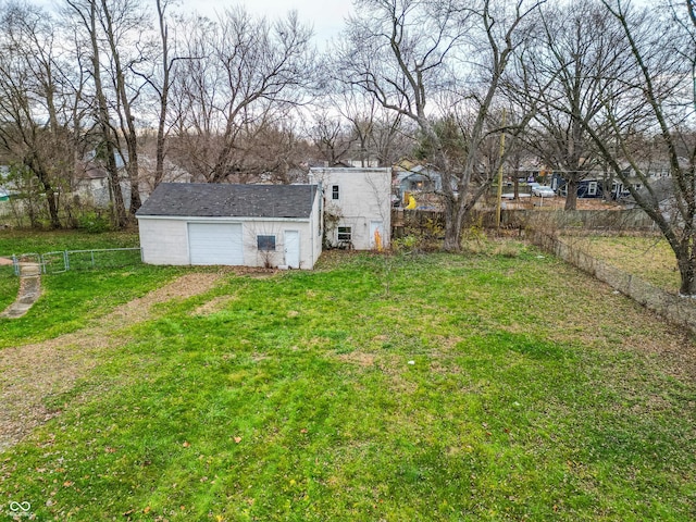 view of yard featuring a detached garage, driveway, and fence