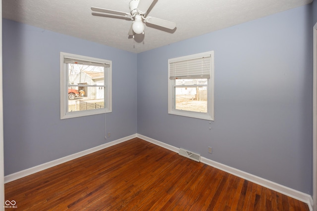 spare room with visible vents, a textured ceiling, baseboards, and dark wood-style flooring