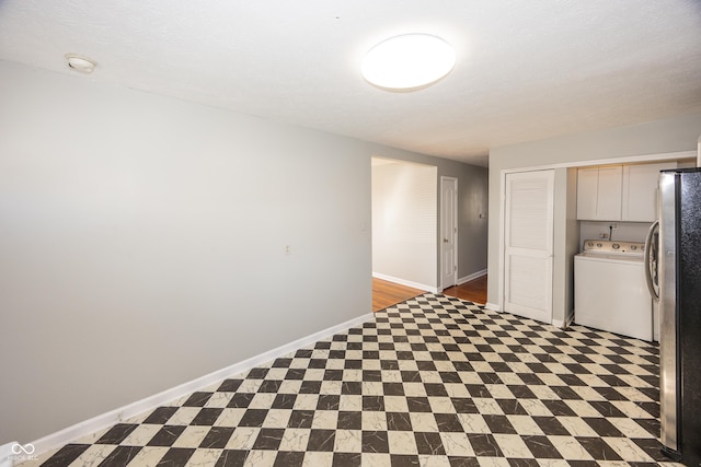 empty room featuring tile patterned floors, baseboards, and washer / dryer