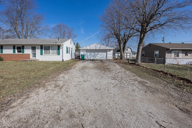 view of front of house featuring an outbuilding, fence, a shingled roof, a front lawn, and a detached garage