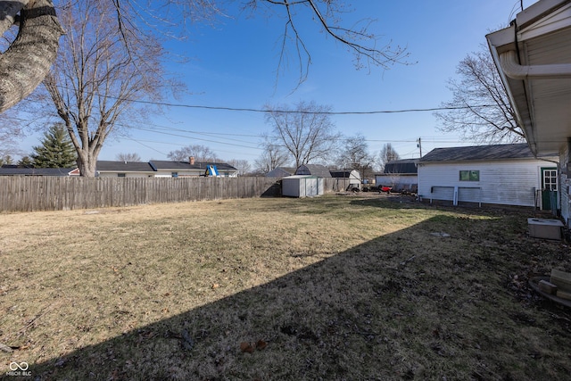 view of yard with a storage unit, an outbuilding, and fence