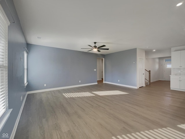 unfurnished living room with light wood finished floors, stairs, and baseboards