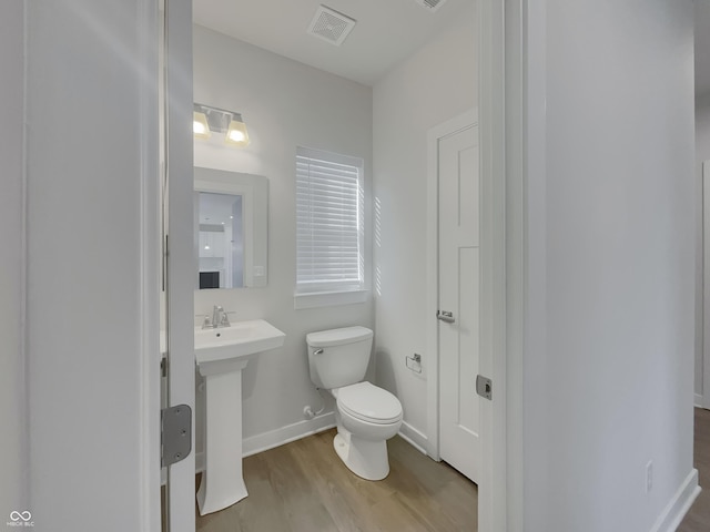 bathroom featuring visible vents, toilet, a sink, wood finished floors, and baseboards