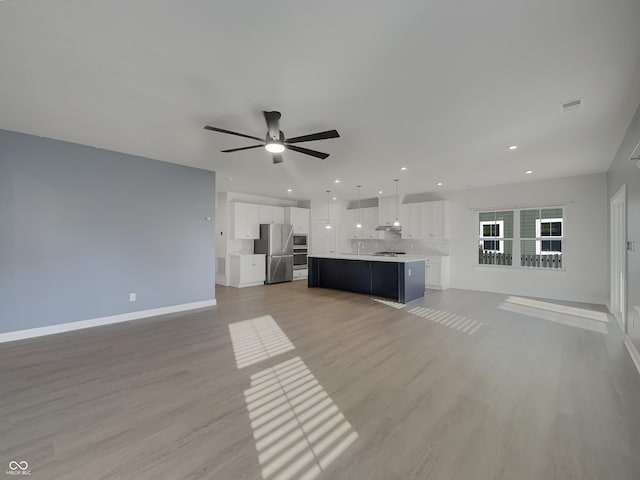 unfurnished living room featuring baseboards, recessed lighting, a sink, ceiling fan, and light wood-type flooring