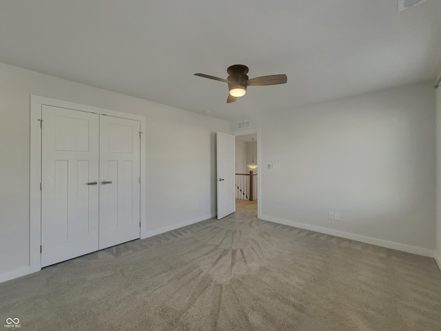 unfurnished bedroom featuring visible vents, baseboards, ceiling fan, a closet, and light carpet