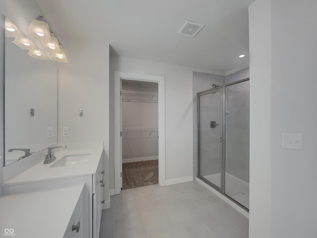 full bath with vanity, baseboards, visible vents, a stall shower, and a walk in closet