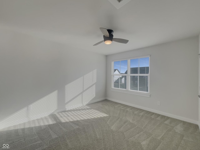 empty room with light colored carpet, a ceiling fan, and baseboards