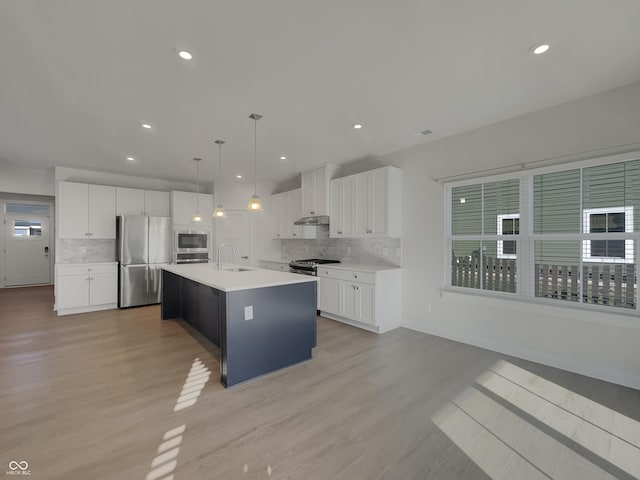 kitchen featuring light wood finished floors, appliances with stainless steel finishes, light countertops, and a sink