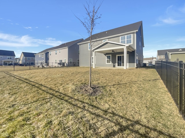 rear view of house with a lawn, a residential view, a fenced backyard, and ceiling fan