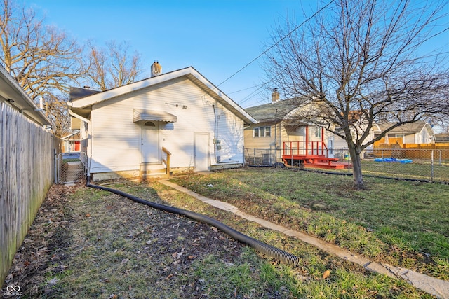 back of property with a gate, a fenced backyard, and a lawn