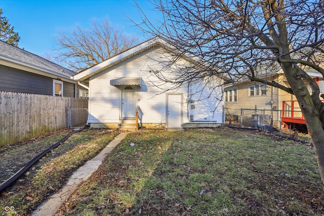 back of property with entry steps, fence private yard, a yard, and a gate