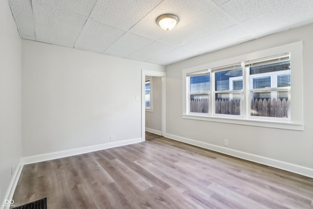 spare room with visible vents, baseboards, and wood finished floors