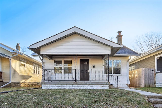 bungalow-style home with a porch, a chimney, and fence