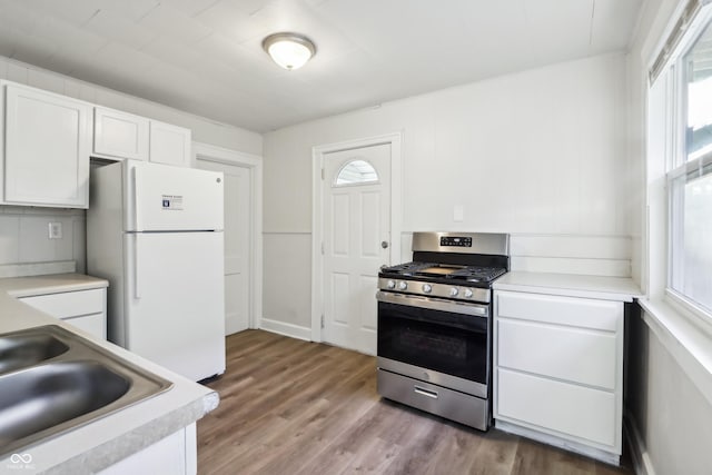 kitchen with stainless steel gas range, freestanding refrigerator, a sink, light countertops, and white cabinetry