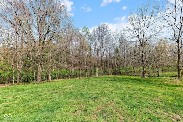 view of yard with a forest view and fence