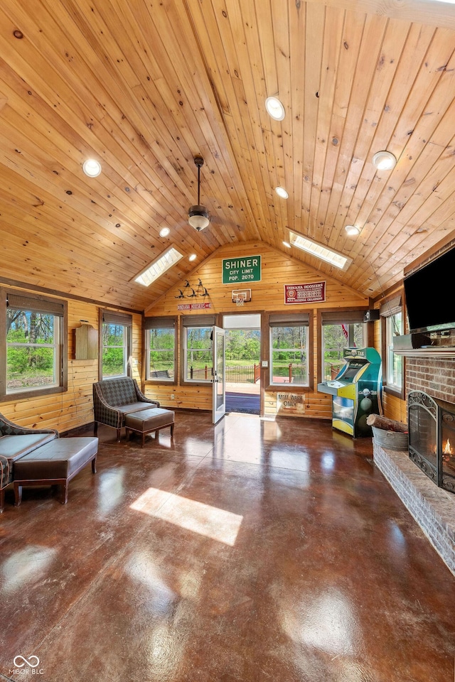 game room with concrete floors, a brick fireplace, vaulted ceiling, and wooden walls