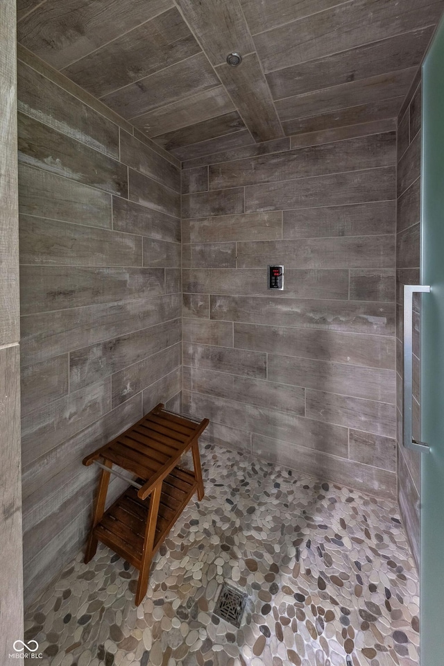 full bathroom with wooden walls, wood ceiling, and a tile shower