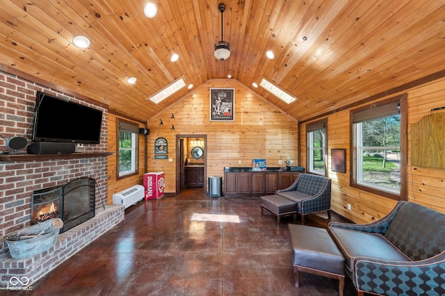 sitting room with finished concrete floors, a brick fireplace, lofted ceiling with skylight, and wooden walls