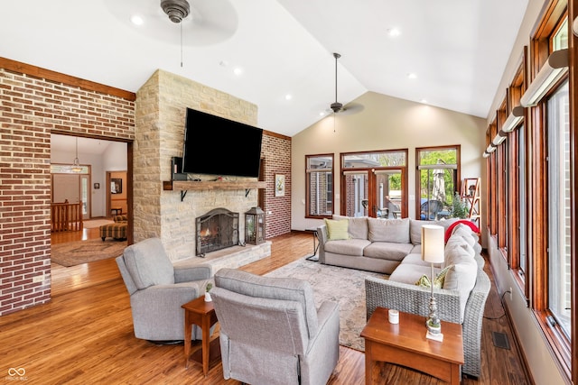 living room with a fireplace, high vaulted ceiling, a ceiling fan, wood finished floors, and visible vents