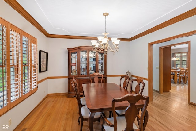 dining room with an inviting chandelier, baseboards, crown molding, and light wood finished floors