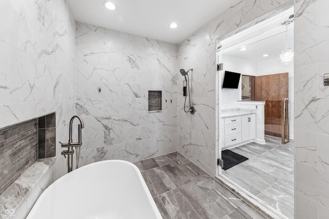 bathroom featuring vanity, marble finish floor, tile walls, recessed lighting, and a soaking tub