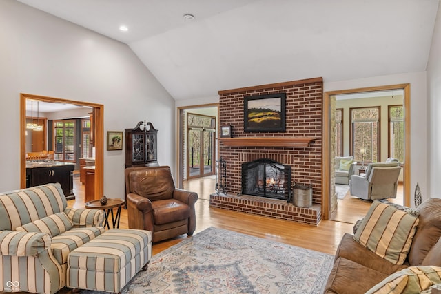 living area featuring a brick fireplace, wood finished floors, and lofted ceiling
