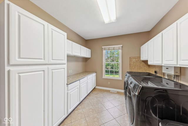 clothes washing area with washing machine and dryer, cabinet space, light tile patterned floors, baseboards, and water heater