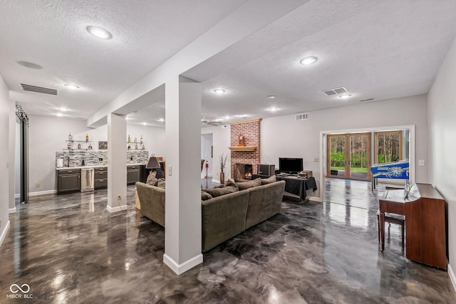 living area featuring visible vents, a textured ceiling, concrete flooring, and indoor bar