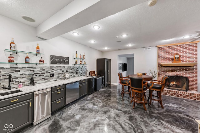 bar featuring backsplash, wet bar, a textured ceiling, stainless steel dishwasher, and a sink