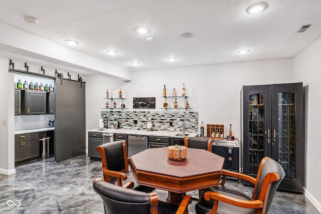 dining space featuring bar, a textured ceiling, finished concrete floors, a barn door, and wine cooler