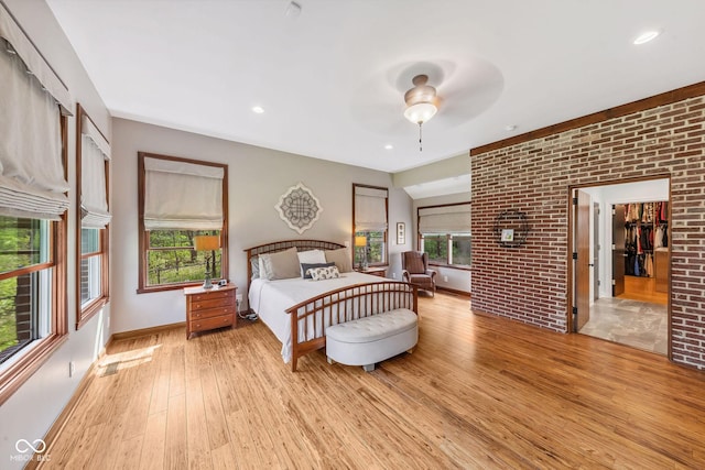 bedroom featuring recessed lighting, baseboards, light wood-style flooring, and brick wall