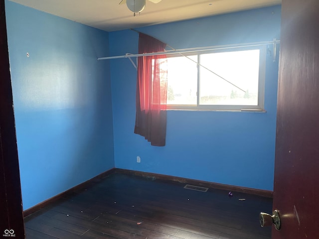 spare room with visible vents, baseboards, and wood-type flooring