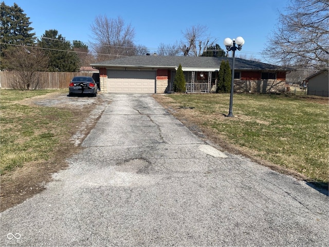 ranch-style home featuring a front lawn, driveway, fence, an attached garage, and brick siding