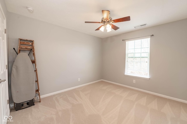 empty room with ceiling fan, visible vents, baseboards, and light carpet