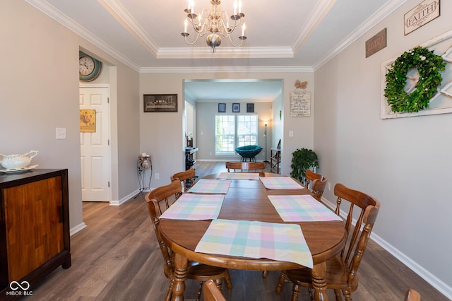 dining room with a tray ceiling, a notable chandelier, wood finished floors, and baseboards