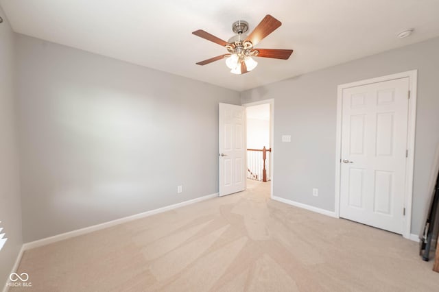 unfurnished bedroom featuring light colored carpet, baseboards, and ceiling fan