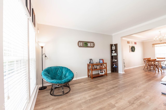 living area with a chandelier, light wood-type flooring, baseboards, and ornamental molding