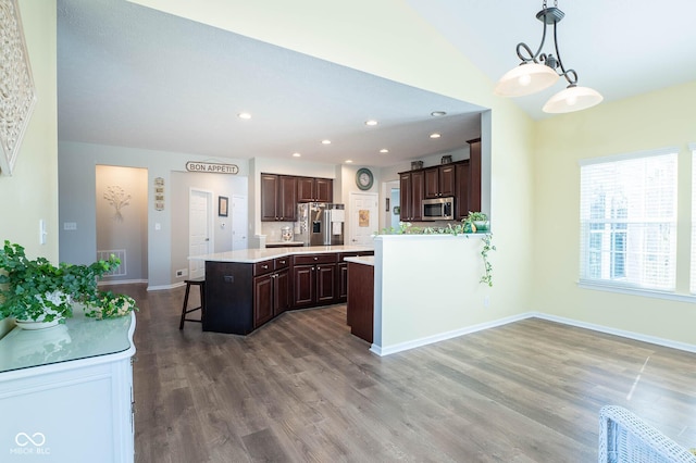 kitchen with stainless steel appliances, a kitchen breakfast bar, dark brown cabinets, and light countertops