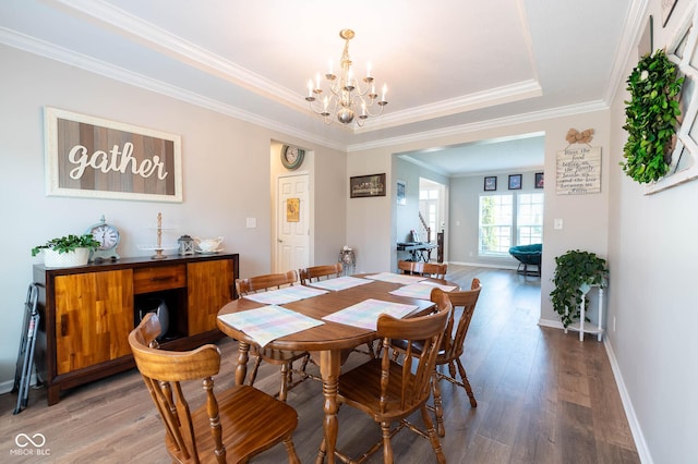 dining space featuring baseboards, an inviting chandelier, light wood-style floors, crown molding, and a raised ceiling