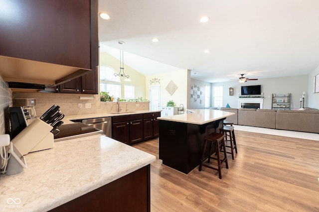 kitchen featuring dark brown cabinetry, a breakfast bar area, light wood-type flooring, a fireplace, and a sink