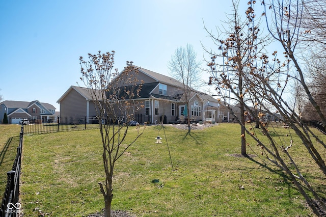 rear view of property featuring a lawn and fence