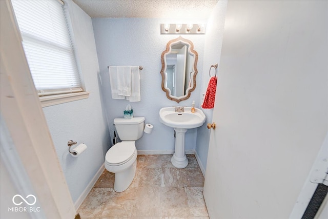 half bath featuring toilet and baseboards