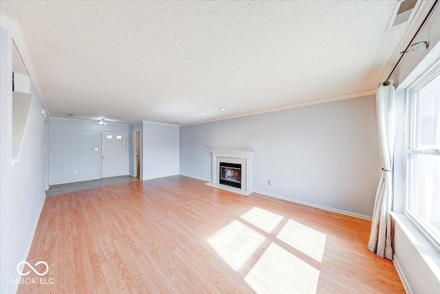 unfurnished living room featuring a fireplace with flush hearth, light wood-style floors, baseboards, and a textured ceiling