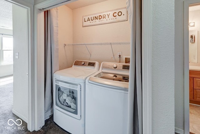 washroom featuring laundry area, a textured wall, and washing machine and clothes dryer